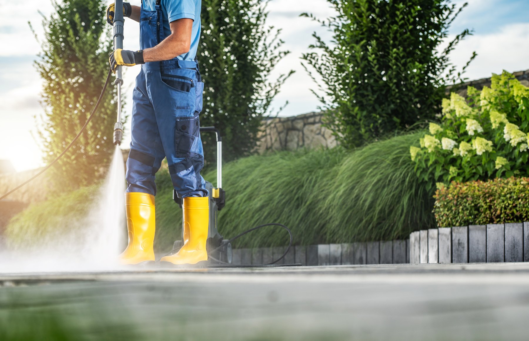 Caucasian Garden Worker Pressure Washing Residential Driveway Using Modern Pressure Washer